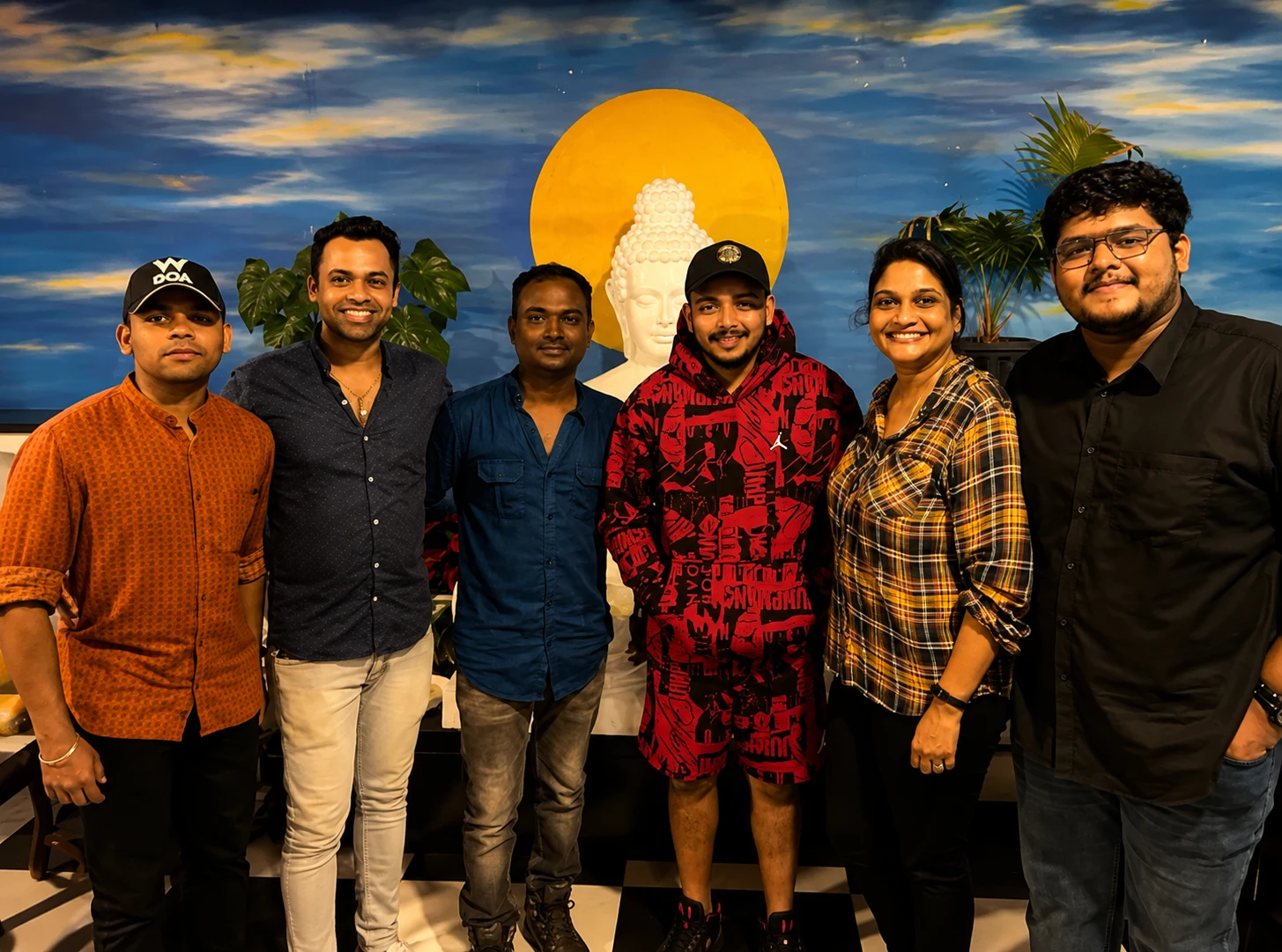 A group of six in front of the painted Buddha mural